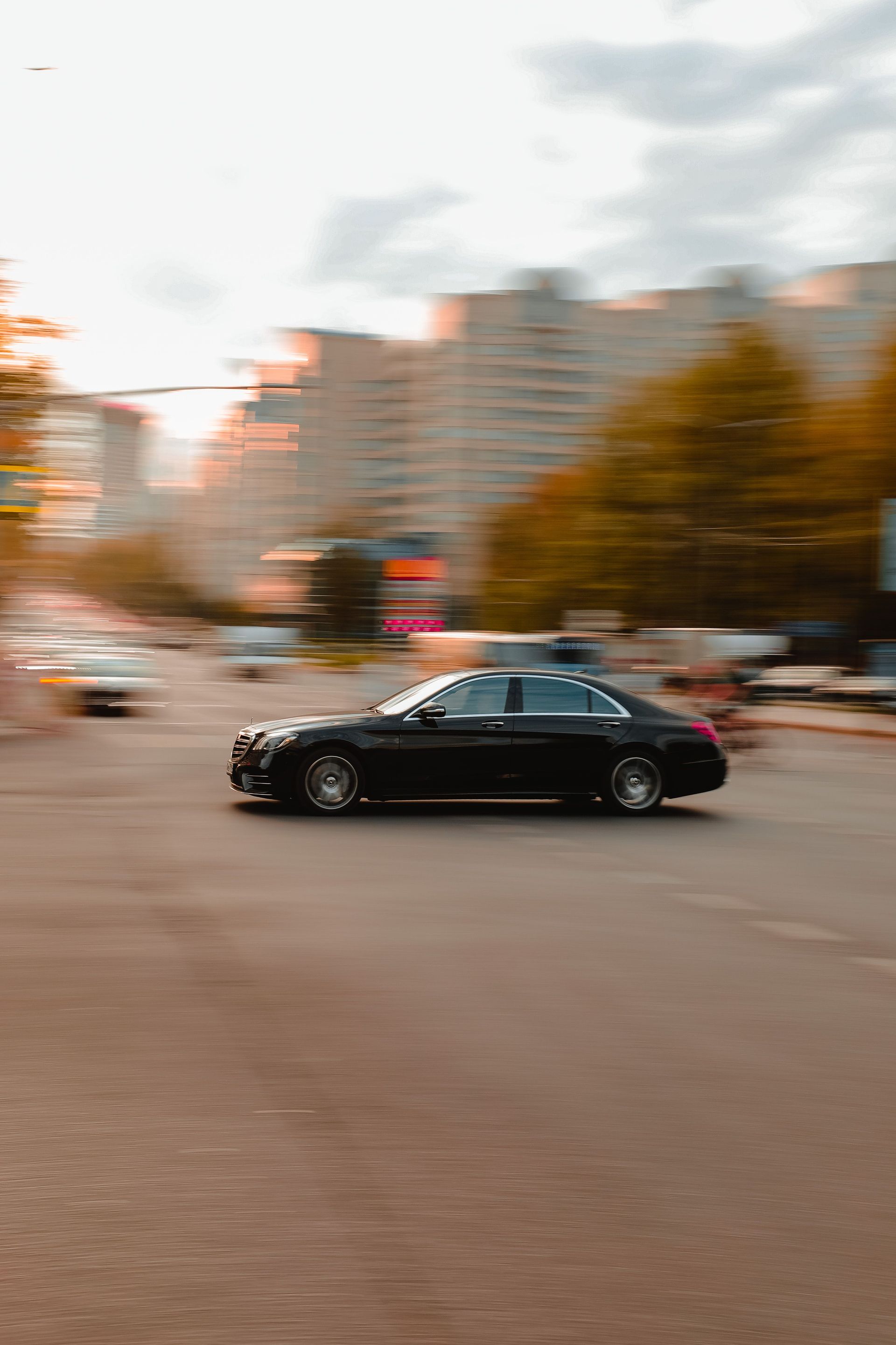 Black luxury sedan speeding on a city street with blurred motion effect.